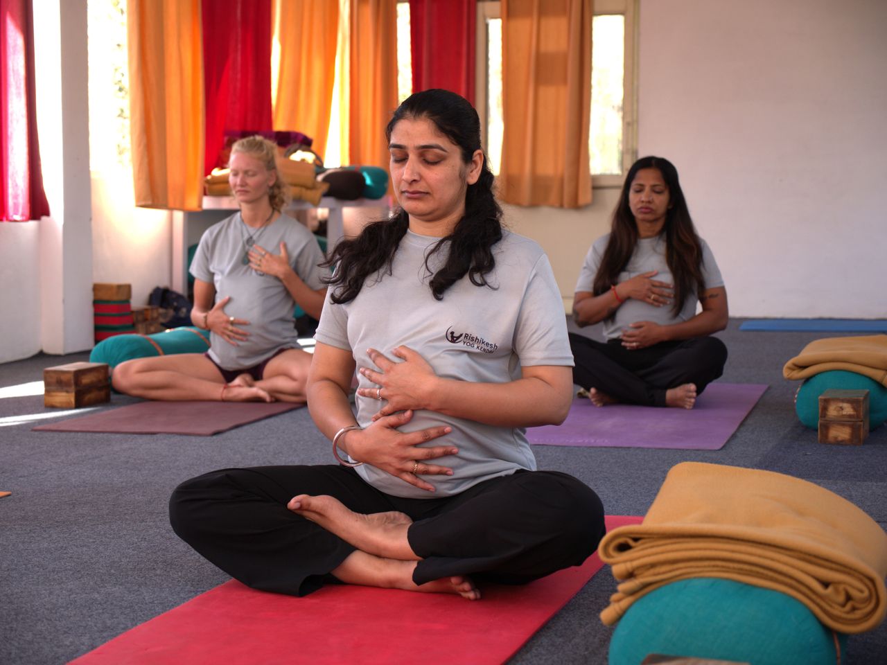Pregnant women practicing calming prenatal yoga in a serene Rishikesh studio.